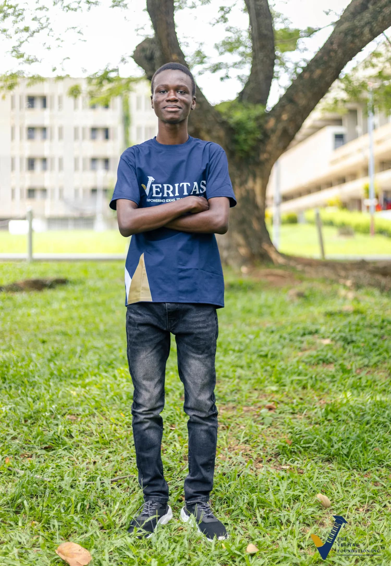 A Veritas scholar standing outdoors in a blue Veritas shirt