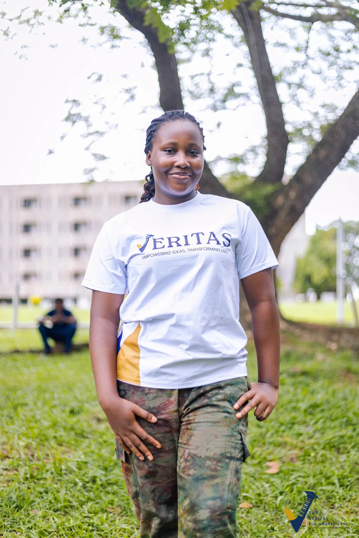 A Veritas scholar smiling outdoors in a white Veritas shirt