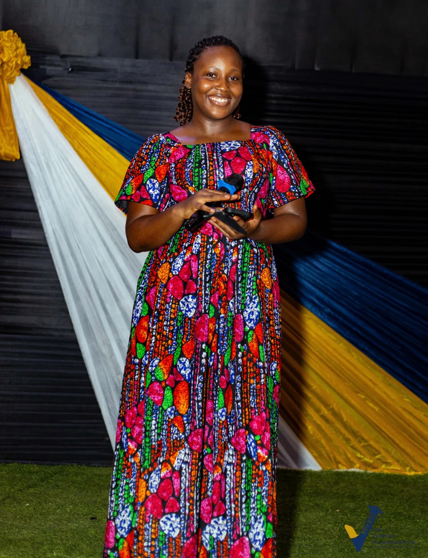 A speaker smiling with a microphone at the Veritas dinner