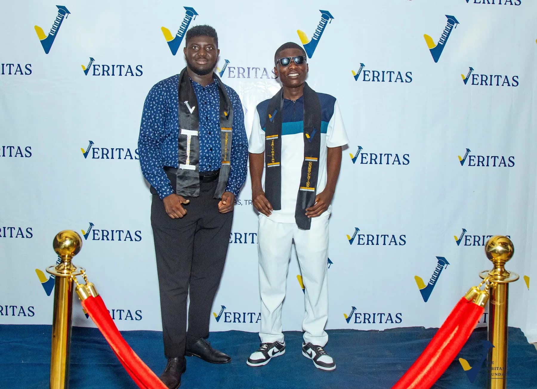 Guests posing beside the Veritas dinner backdrop